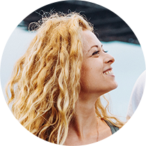 A headshot of a person with long, strawberry-blond hair smiling in profile.
