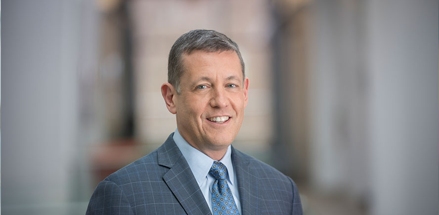 null Head shot of Colin Kelton, Director, wearing a blue business suit and tie smiling at the camera.