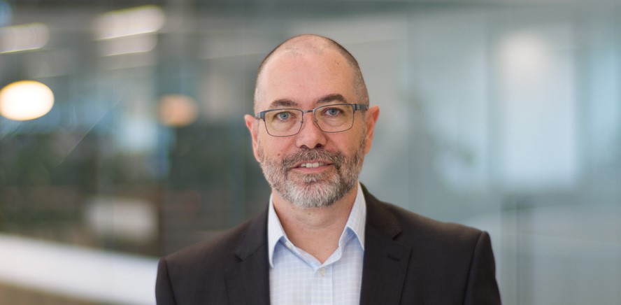 null Head shot of Craig Stevens, Head of Strategic Growth and Service Delivery, smiling at the camera.